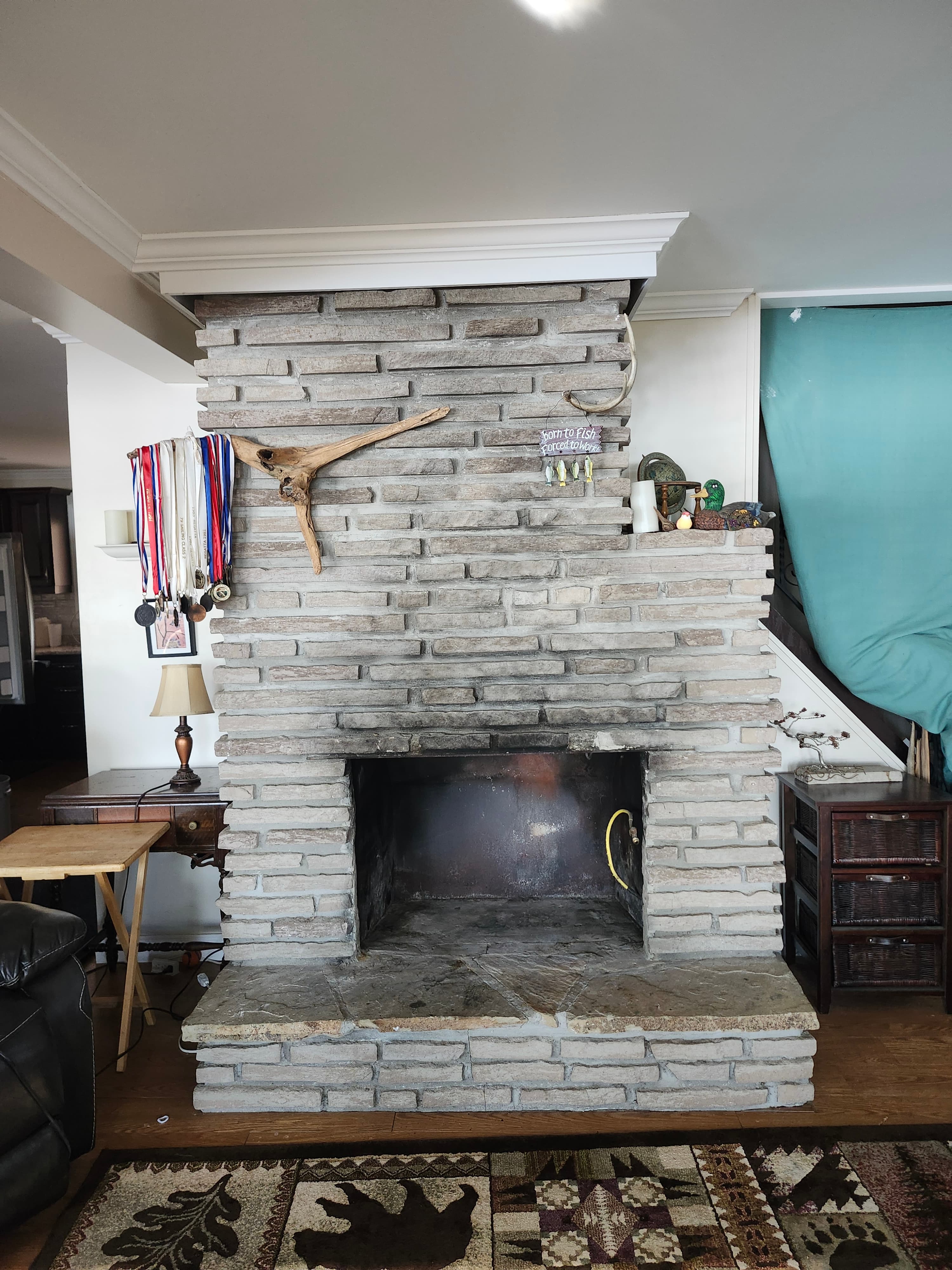 Light gray brick fireplace with driftwood and medals, next to a bear-patterned area rug.